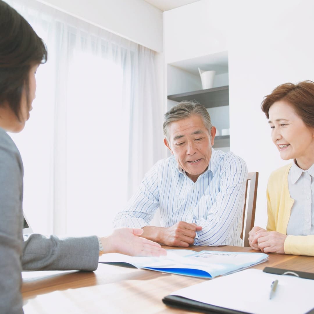 An adviser talking an older couple through printed information across a table.